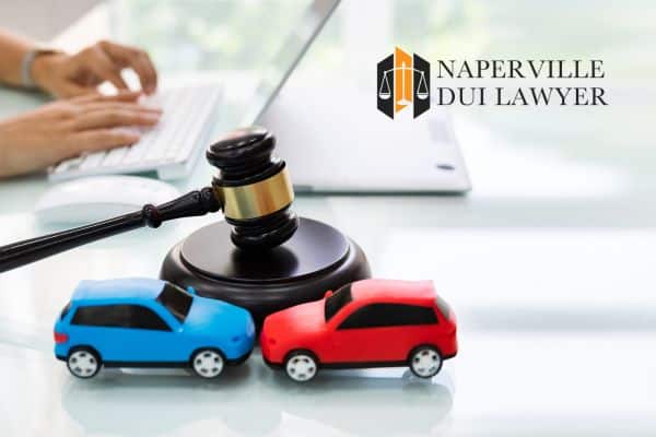 someone working on an insurance policy with two toy cars and a gavel beside them