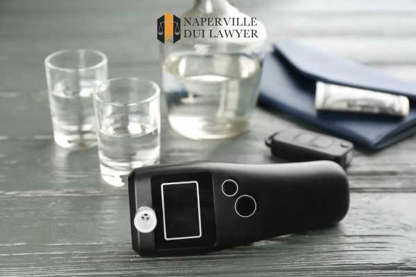 a breathalyzer and shots of alcohol on a table
